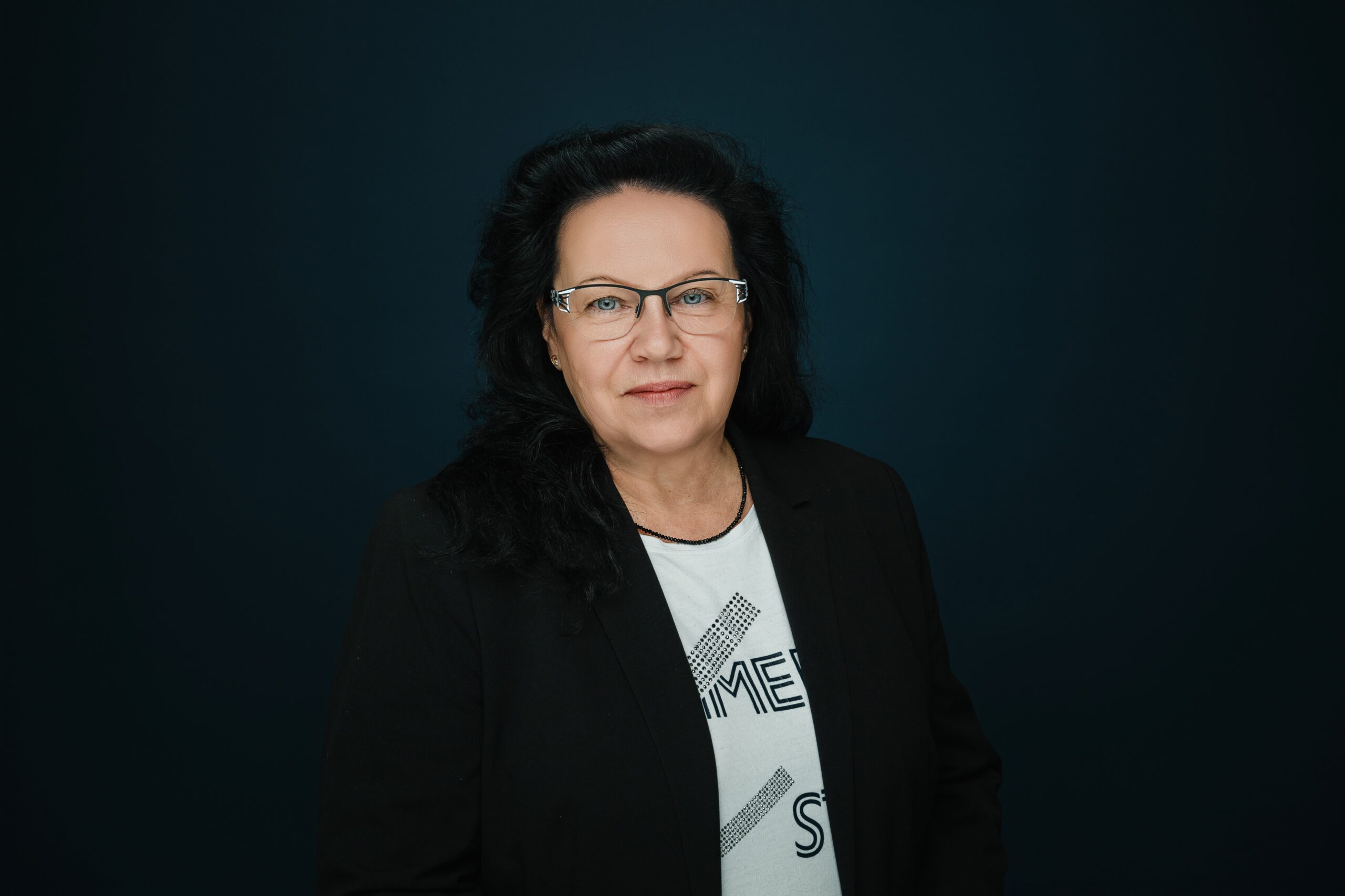 Foto von Diana Tietze in schwarzer Jacke vor dunklen Hintergrund.